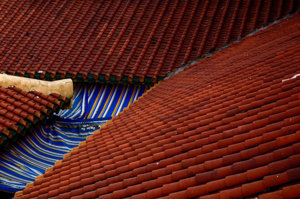 A close-up of traditional red-tiled rooftops with a vibrant blue and yellow patterned fabric.